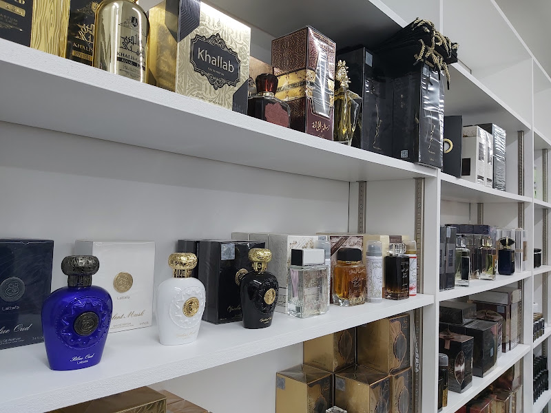 White shelving stacked with boxed perfumes and attar bottles in gold and black packaging