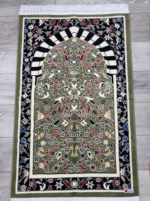 Green floral prayer mat with a woven mihrab arch design laid flat
